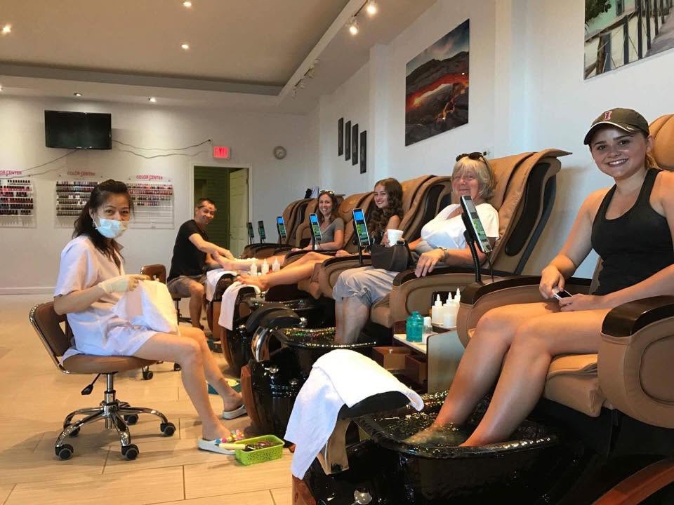 Clients having pedicures in the salon's massage chairs while technicians work